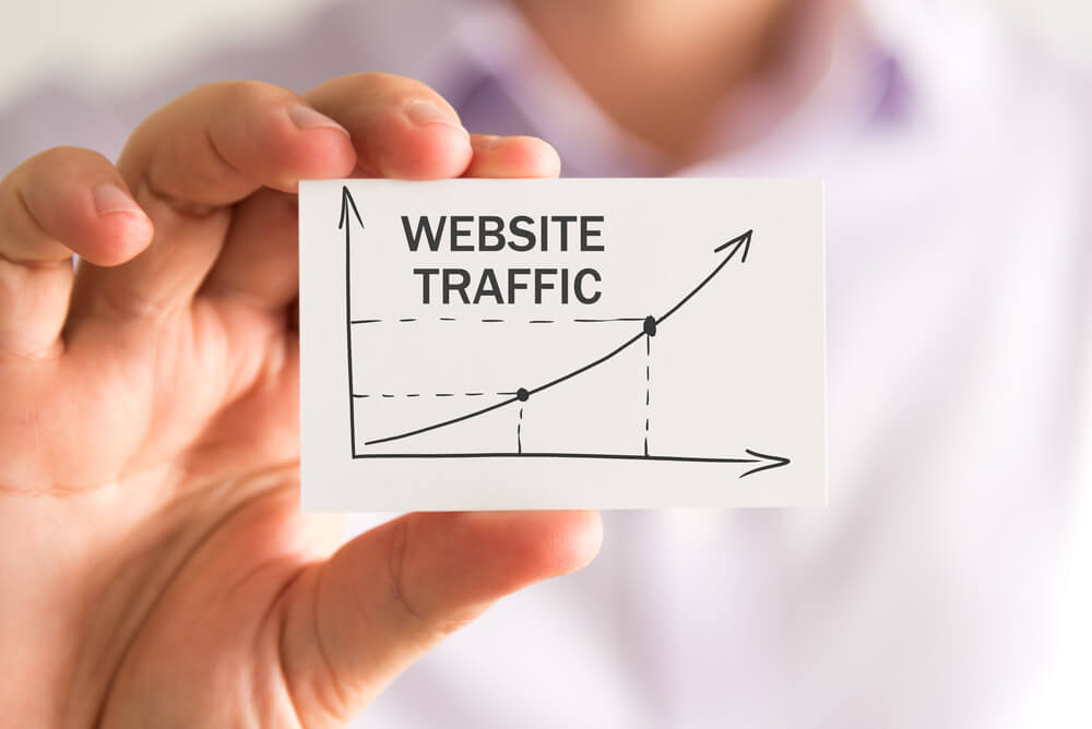 website traffic_Closeup on businessman holding a card with WEBSITE TRAFFIC rising arrow and chart, business concept image with soft focus background