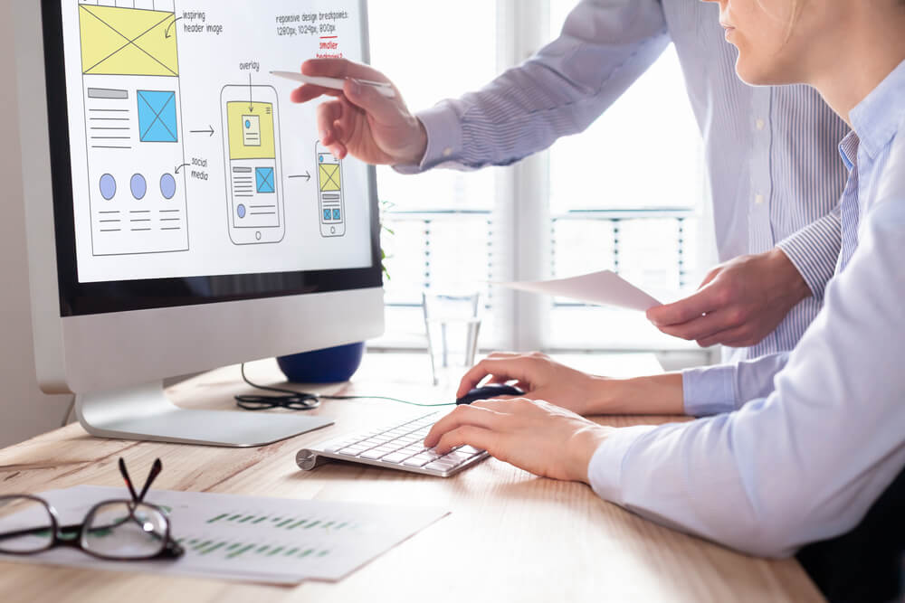 user experience_Website development team sketching wireframe layout design for responsive web content, two UI/UX front end designers in office