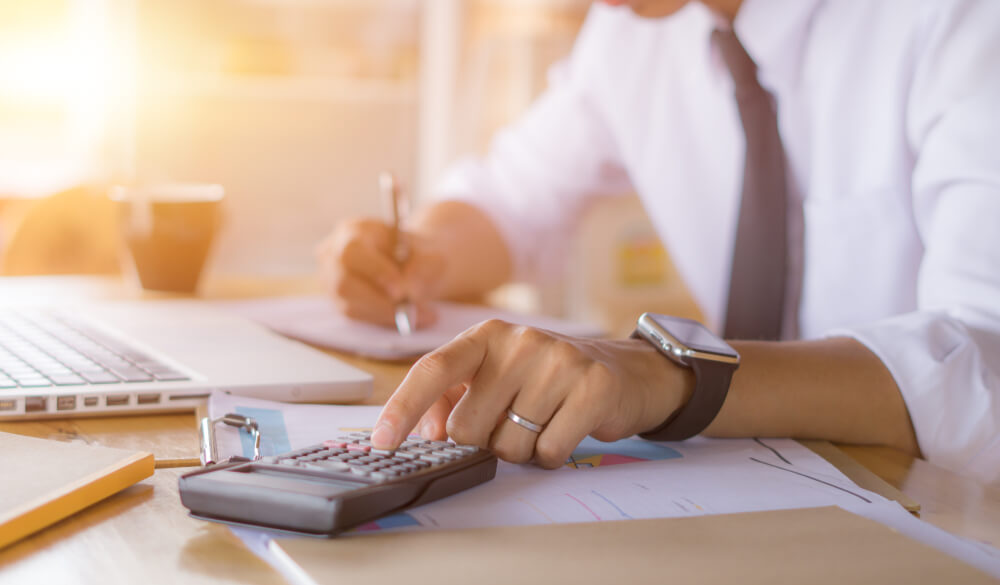 seo cost_Businessman accountant using calculator and laptop for calculating finance on desk office. business financial accounting concept.