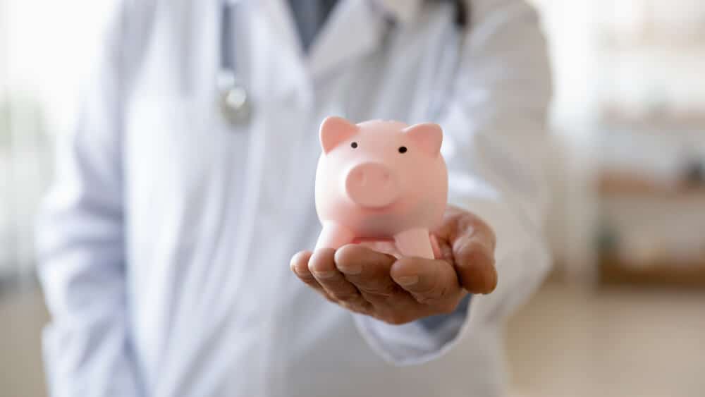 therapist budget_Crop close up of male GP or physician hold piggybank collect volunteer monetary donation for hospital needs, man doctor in white medical uniform with piggy bank ask for charity, healthcare concept