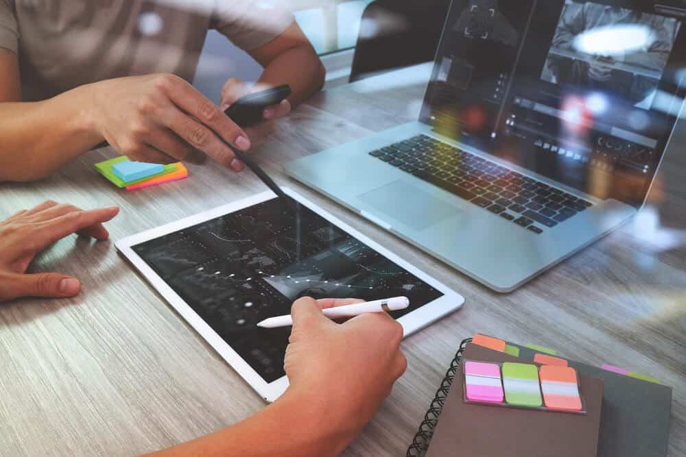 seo strategy_Team meeting. Hand businessman working with new startup project in modern office. Generic design notebook and digital tablet and smart phone on pale wood table. Horizontal, sun flare effect photo