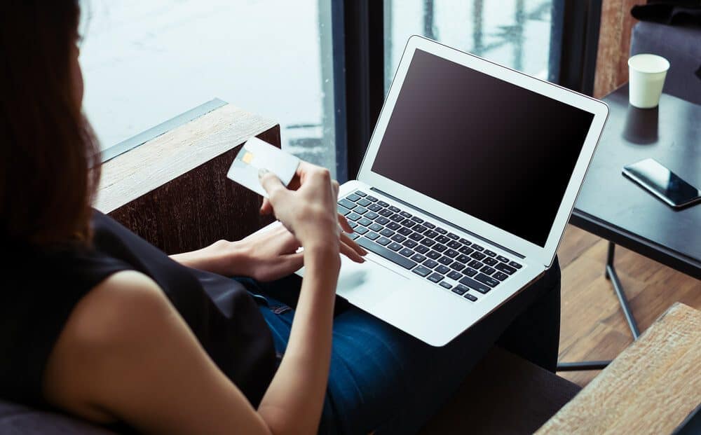 ppc pricing_Woman's hands holding a credit card and using laptop for online shopping.