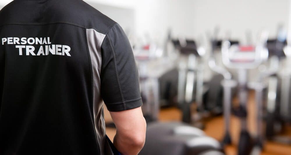 personal trainer_Personal Trainer, with his back facing the camera, looking at a gym