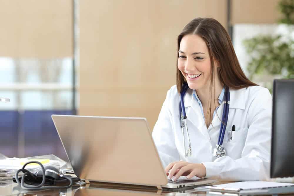 healthcare content_Happy doctor using a laptop writing content at consultation