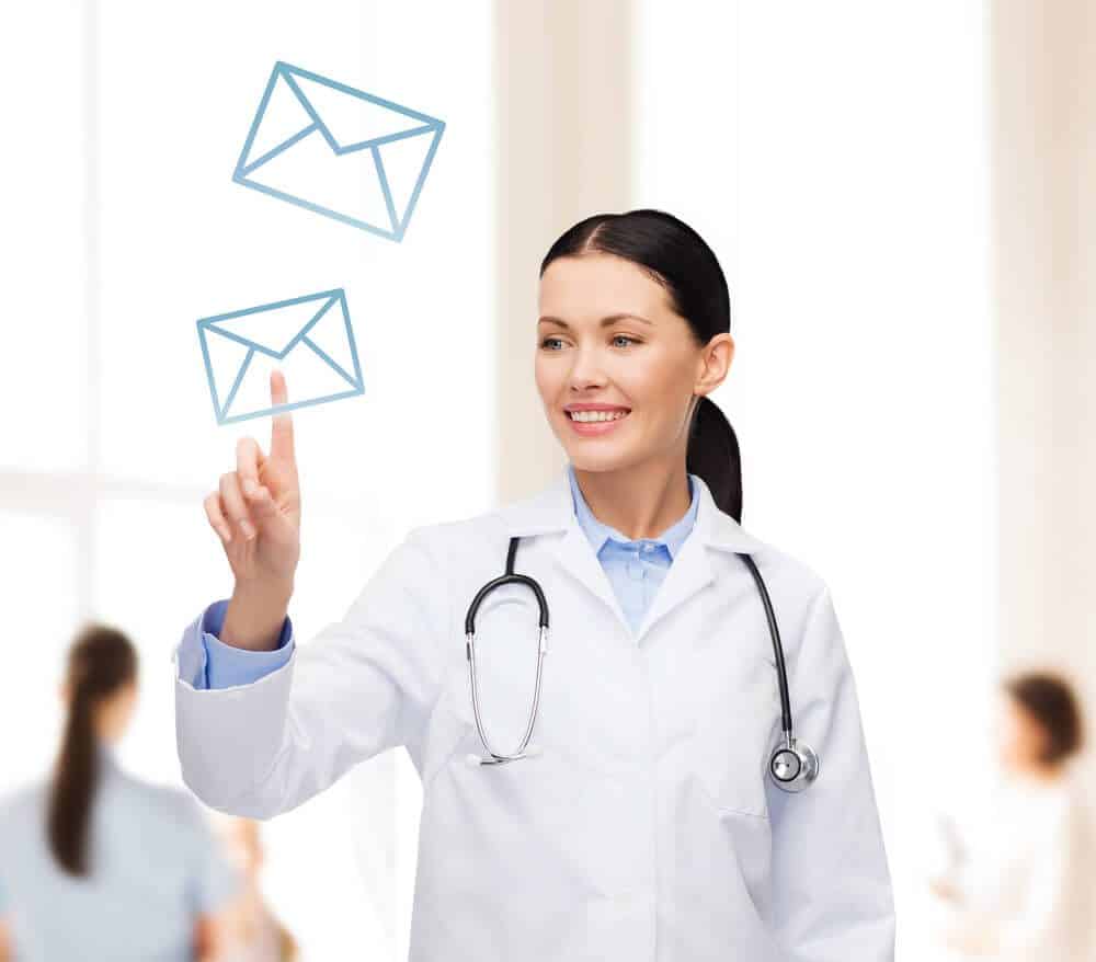 healthcare email_healthcare, medicine and technology concept - smiling female doctor with stethoscope pointing to envelope