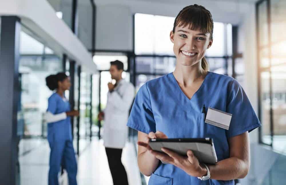 healthcare content_Modern healthcare requires modern technology. Shot of a young doctor using a digital tablet in a hospital with her colleagues in the background.