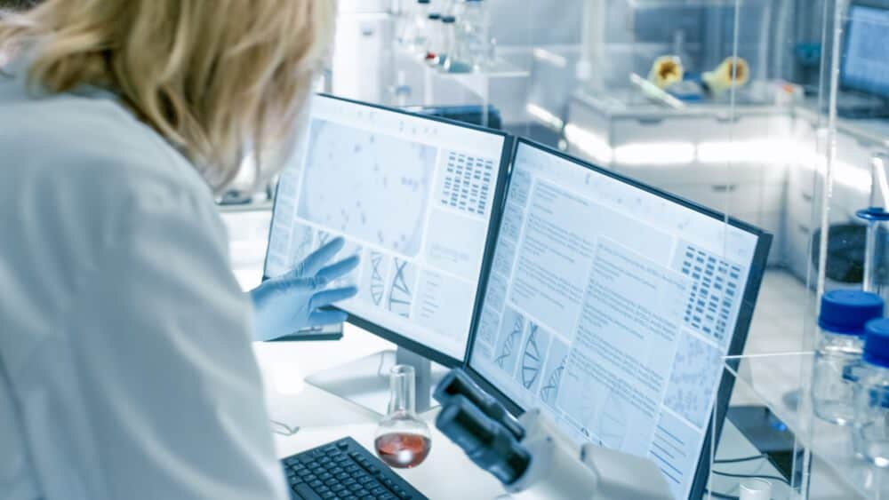 health data_Senior Female Scientist Discusses Scientific Data with Her Laboratory Assistant. They're looking at Two Displays in a Modern Laboratory.