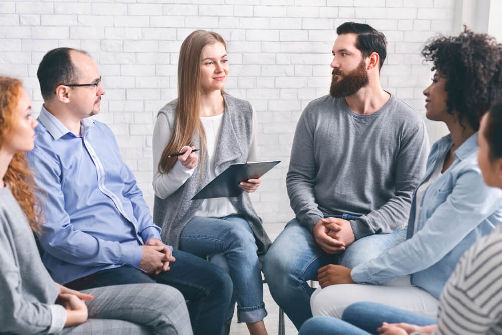 drug rehab center_Meeting Of Support Group. Psychologist talking to addicted people in office