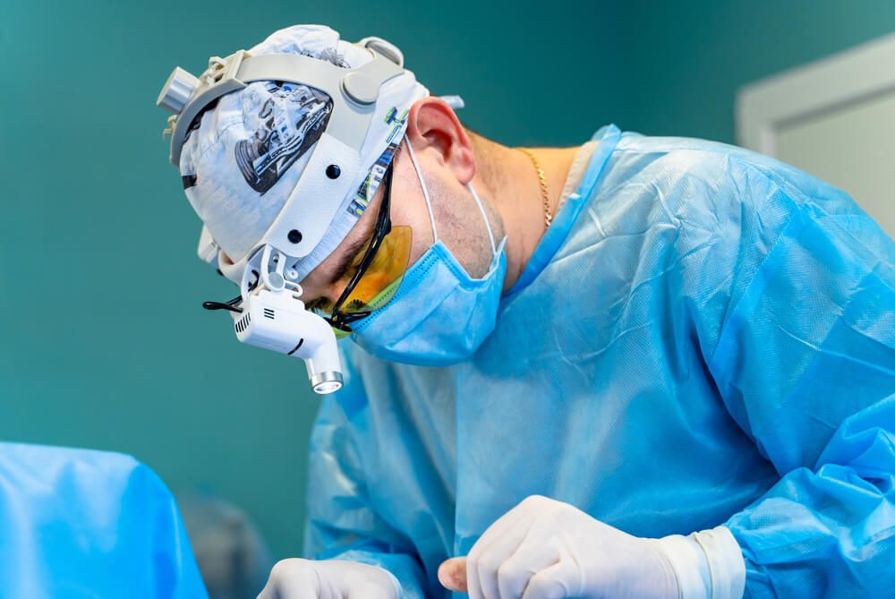 cosmetic surgeon_Surgeon performing cosmetic surgery in hospital operating room. Surgeon in mask wearing surgical light during medical procedure. Plastic surgery concept.