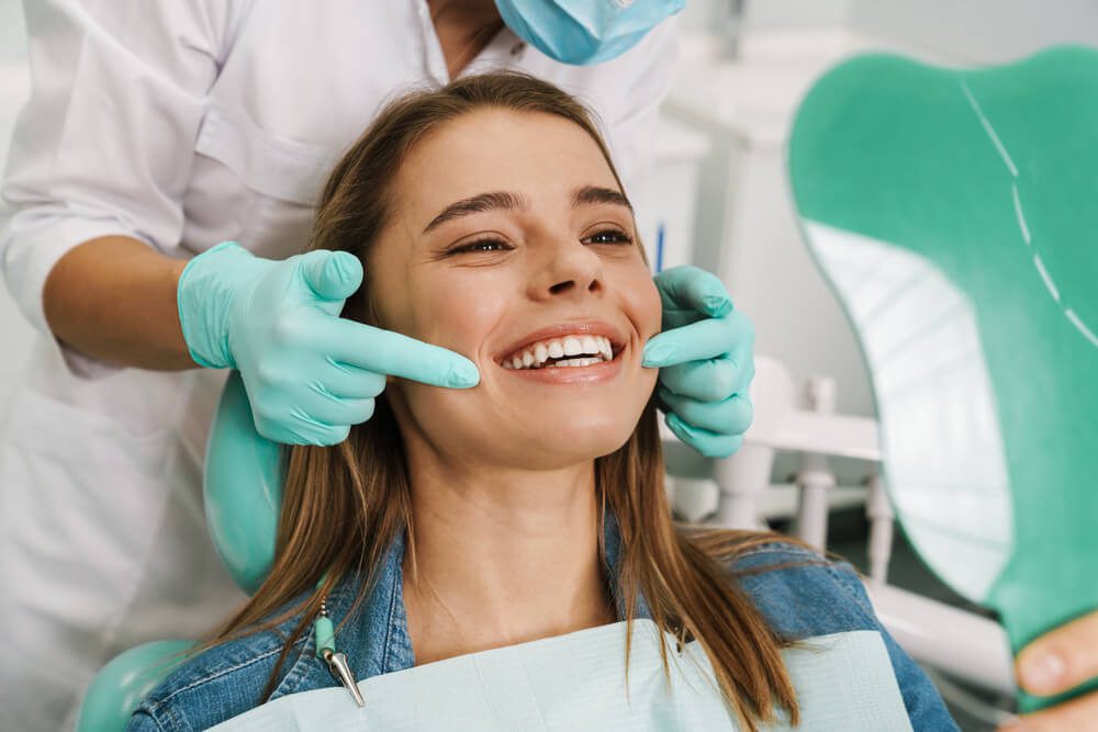 dentist_European young woman smiling while looking at mirror in dental clinic