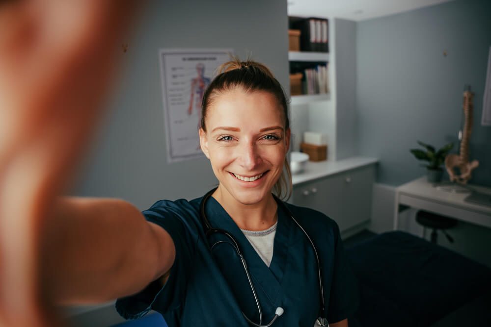 healthcare content_Caucasian female doctor taking selfie in doctors office with cellular device