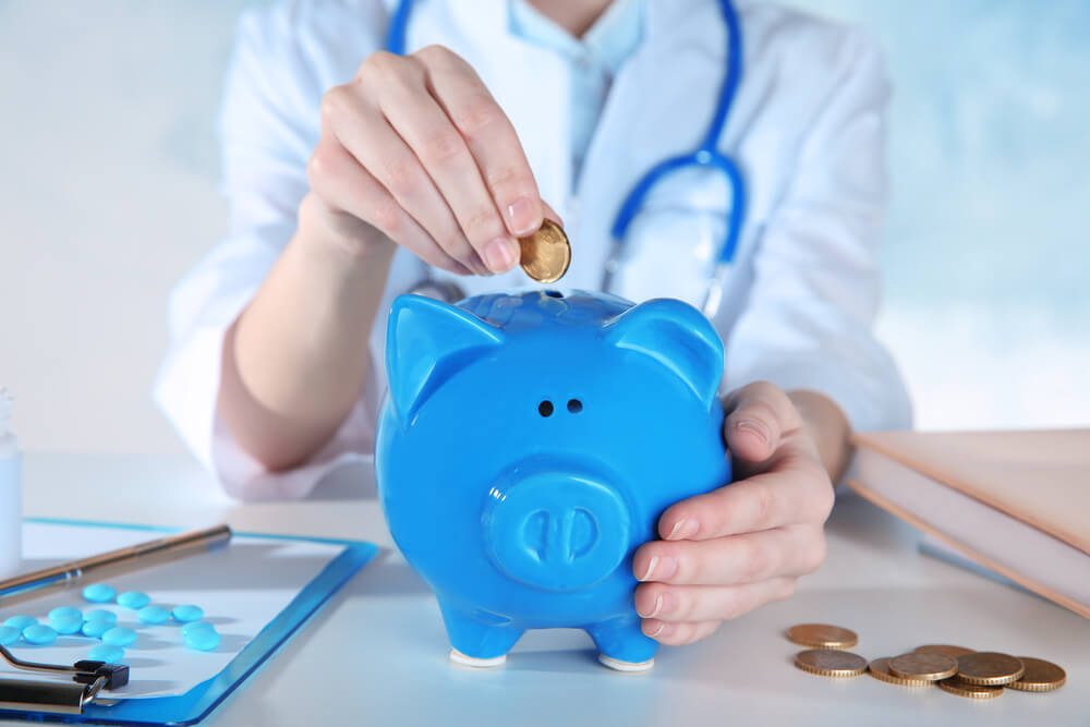 hospital investment_Doctor's hands with piggy bank, closeup