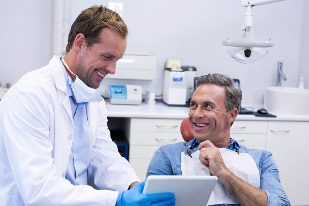 dentist content_Dentist discussing over digital tablet with male patient in dental clinic