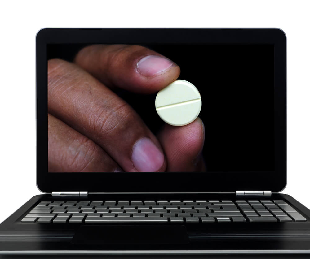 website drug rehab_black laptop showing hand holding illegal drug for sell on illegal website, abuse or bad use of internet.