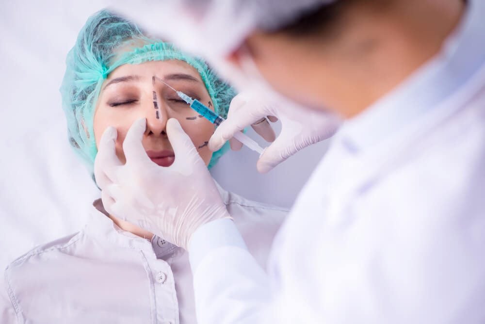 plastic surgeon_Plastic surgeon preparing for operation on woman face