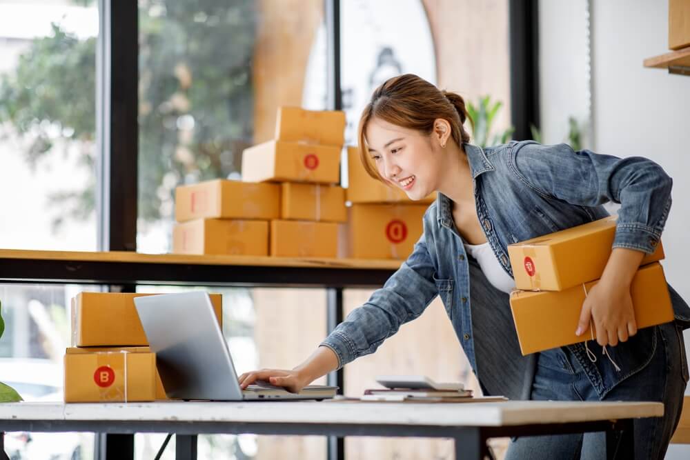 seo for small business_Startup SME small business entrepreneur SME or freelance Asian woman using a laptop with box, Young success Asian woman with her hand lift up, online marketing packaging box and delivery, SME