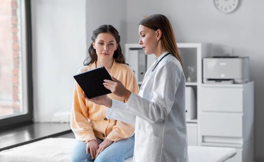 medical patient_medicine, healthcare and people concept - female doctor with tablet pc computer talking to woman patient at hospital