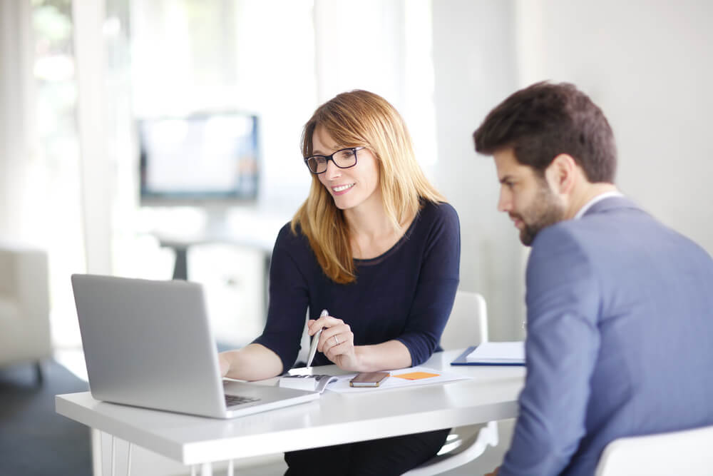 seo consultant_Portrait of investment advisor businesswoman sitting at office in front of computer and consulting with young professional man.