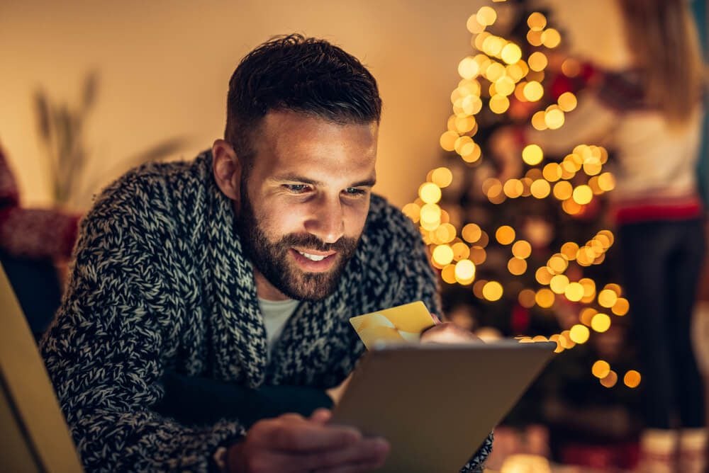 online holiday_Handsome man holding a credit card and shopping on a tablet.