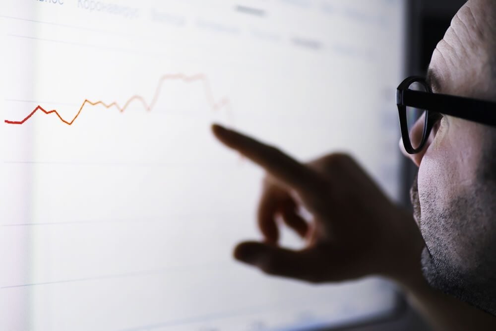 seo graphs_A businessman is looking at a graph on a monitor. An exchange broker evaluates stock market trends. A man with glasses in front of a curve of the dynamics of economy.