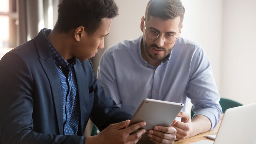 people ask_Diverse businessmen discuss startup project use gadget look at tablet screen, african colleague show to associate new application ask question work together, teamwork with modern wireless tech concept