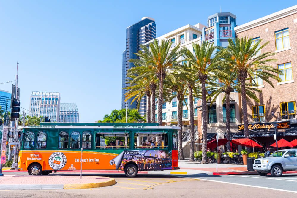 san diego tours_San Diego, California - October 09 2017: Hop On Hop Off Tour Bus with tourists taking a ride in the Gaslamp Quarter district in traffic on the city streets of sunny San Diego, California.