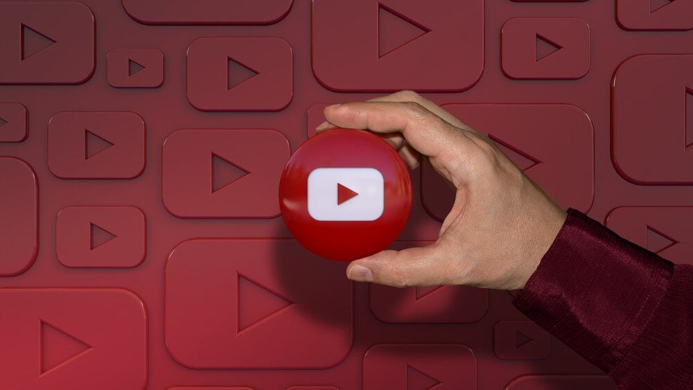 youtube_Buenos Aires, Argentina - January 26, 2021: A hand holding a youtube logo glossy badge over dark red background