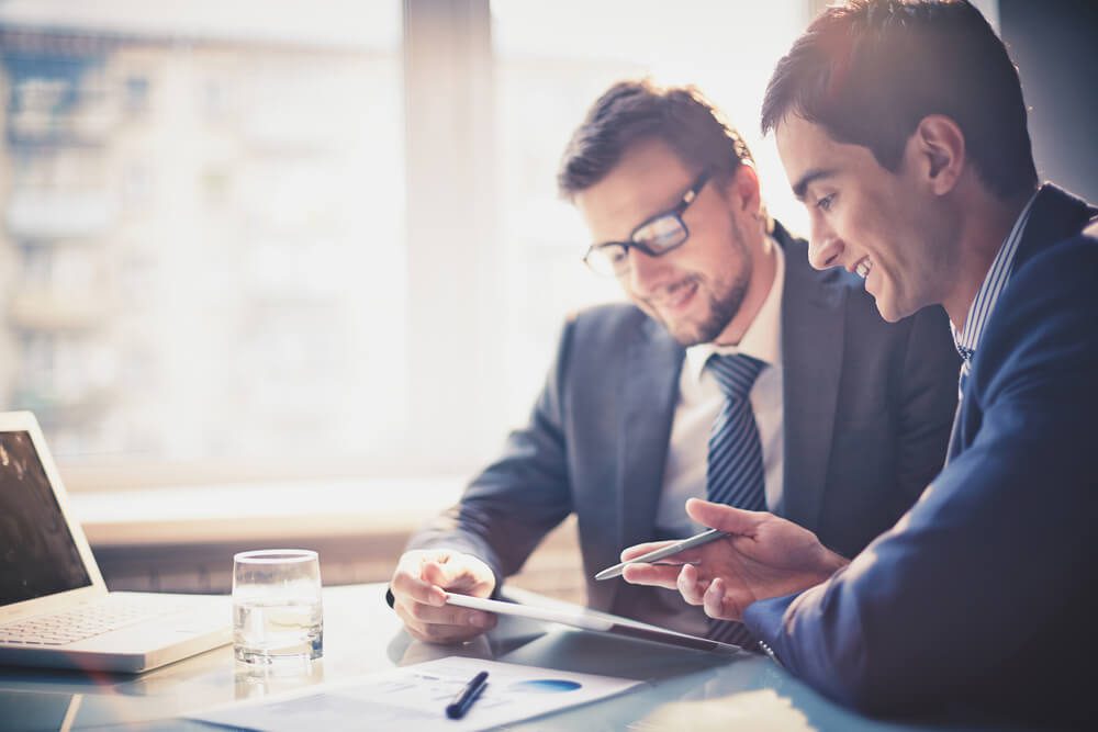 digital marketing consultant_Image of two young businessmen using touchpad at meeting