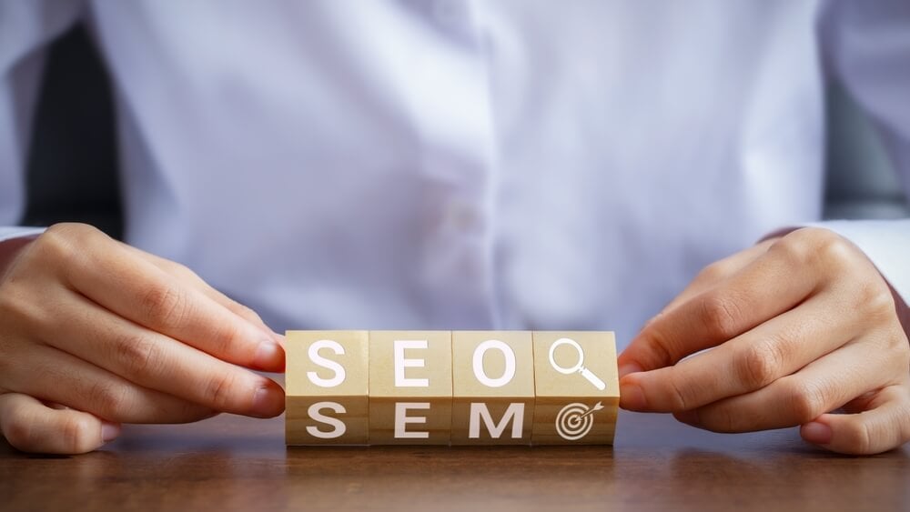 seo sem_Businessman hand holding wooden block with letters SEO and SEM. Concepts about managing search engine based and targeted marketing.