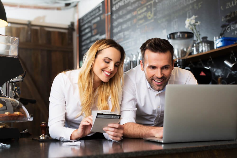 small business_Two happy cafe managers working on laptop