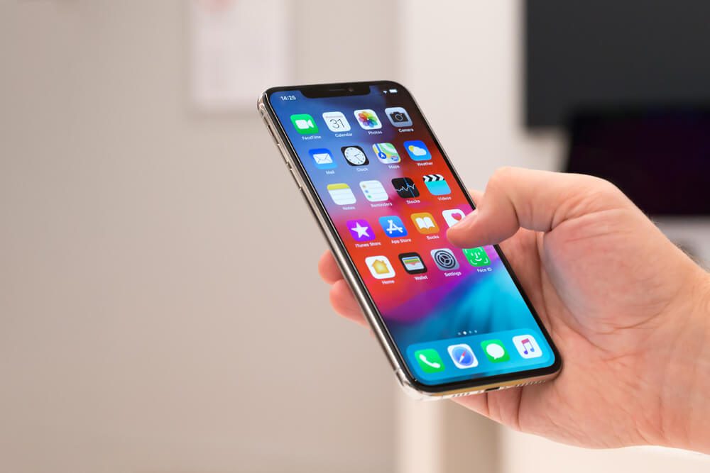 app store_Belgrade, Serbia - October 31, 2018: New Apple iPhone XS mobile smartphone is displayed with apps on the screen in hand. Finger typing on digital gadget in electronic store.