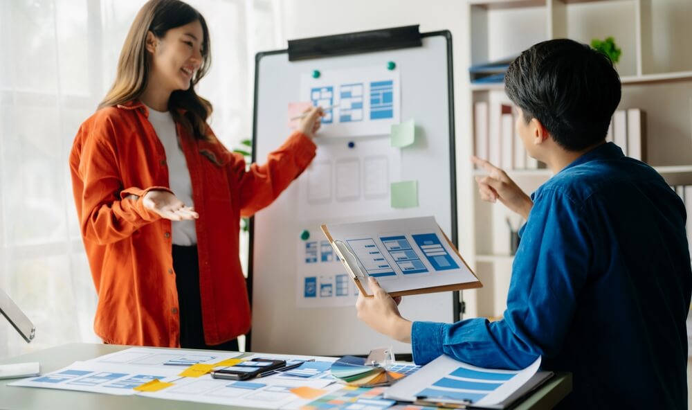 UX design_UX developer and ui designer brainstorming about mobile app interface wireframe design with customer breif and color code at modern office.