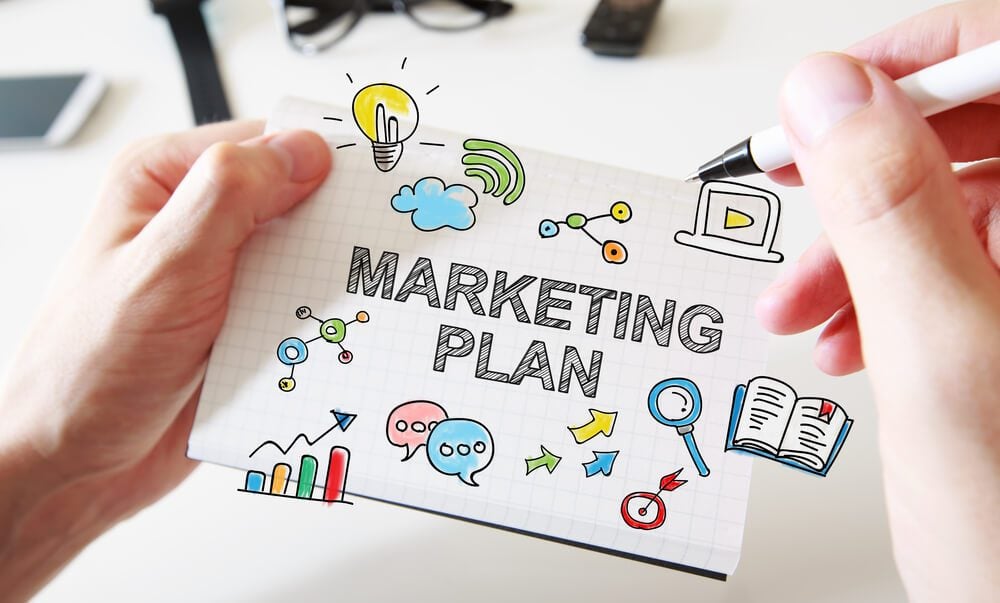 marketing plan_Mans hand drawing Marketing Plan concept on white notebook