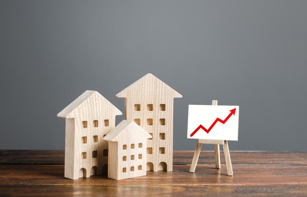 real estate_Residential buildings and easel with a positive growth trend red arrow up chart. Market growth, attracting investment. Raising taxes and house maintenance. Real estate price increases. High value