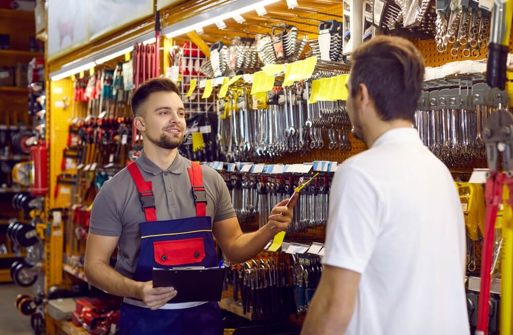 hardware store_Sales assistant at hardware store helping customer choose tools for home repairs. Salesman with clipboard offering good quality wrench to man who has come to DIY store to buy tools for his garage