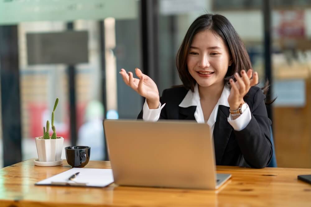 custom software_Happy Asian woman sitting in the office and video conference with a business partner on a laptop. Concept of a new lifestyle and social distancing