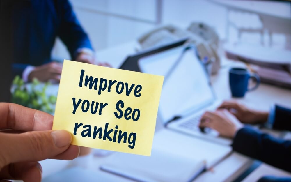 seo_Male hand holding sticky note written Improve your Seo ranking.