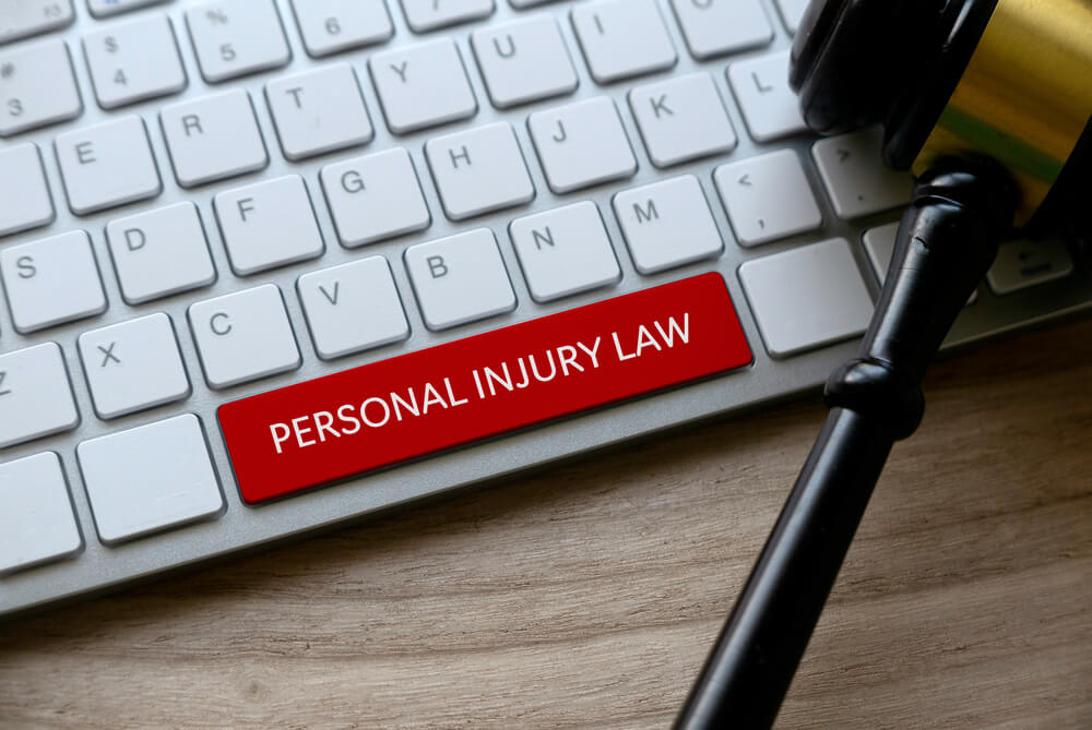 personal injury law_Selective focus of gavel and computer keyboard with red key written with Personal Injury Law on a wooden background.
