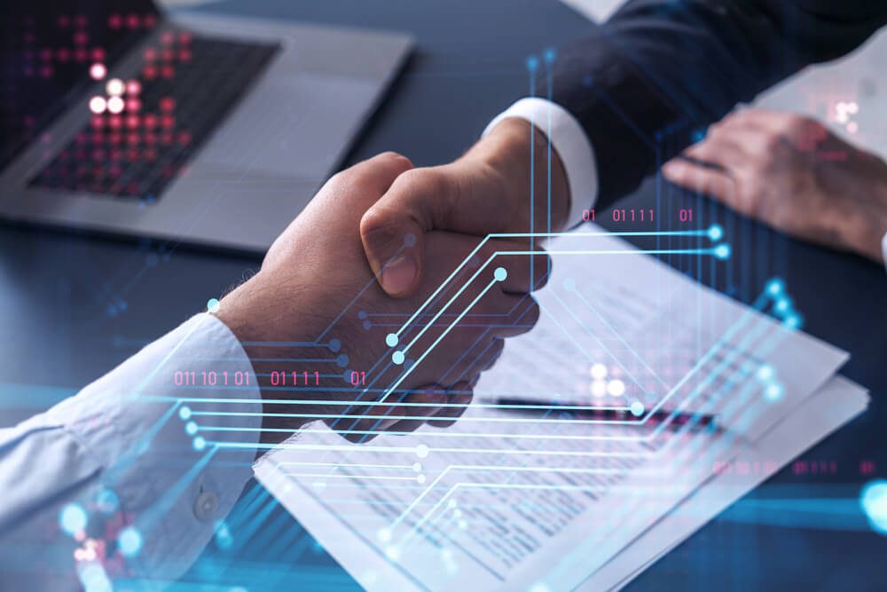 custom software development_Handshake of two businessmen who enters into the contract to develop a new software to improve business service at a company. Technological icons over the table with the document.