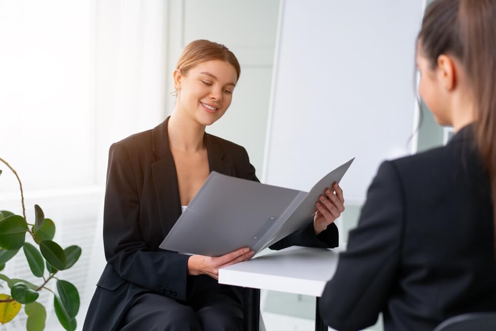 CMO_Job interview. Business, career and placement concept. Young blonde woman holding resume, while sitting in front of candidate during corporate meeting. Boss discuss ideas with partner. Handshaking