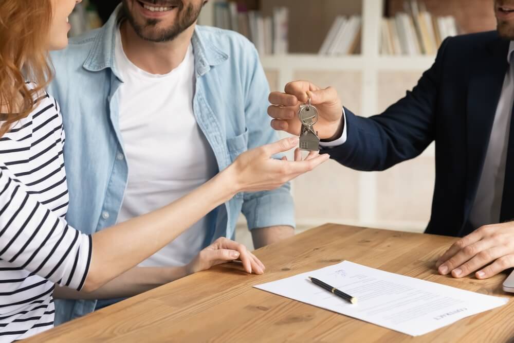 real estate leads_Cropped close up view happy couple receiving keys from new own property, finish meeting in real estate agency lead by realtor in formal suit. Bank mortgage for young family, selling, renting concept