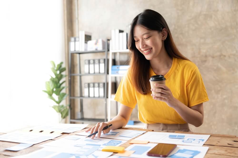 UX designer_Young asian designer woman drawing a website outline and website ux app development on mobile phone.