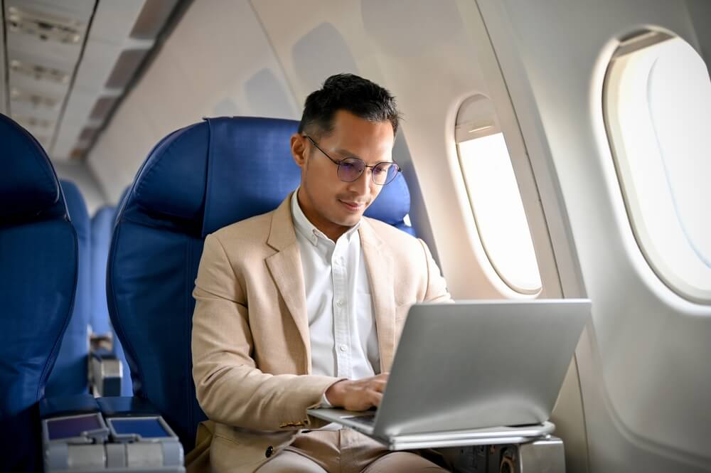 luxury travellers_A professional and focused businessman or male CEO using a laptop computer, typing on the keyboard, managing his business tasks during the flight.