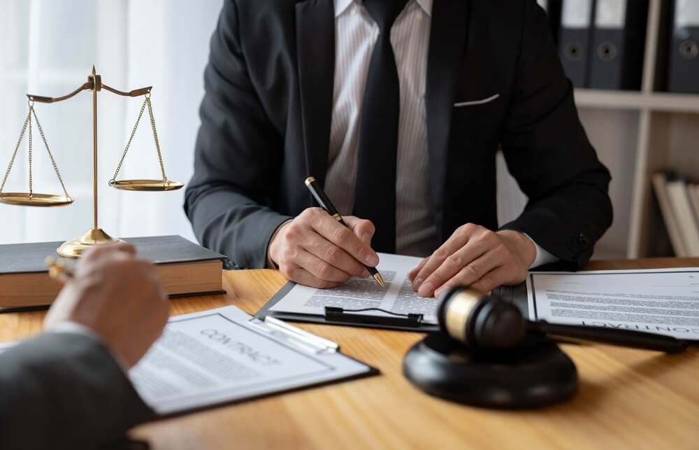 personal injury law_Lawyer, legal advisor, Asian businessman explaining agreement details Business contracts to investors and brainstorming Take notes for accuracy in the document before signing the contract together.