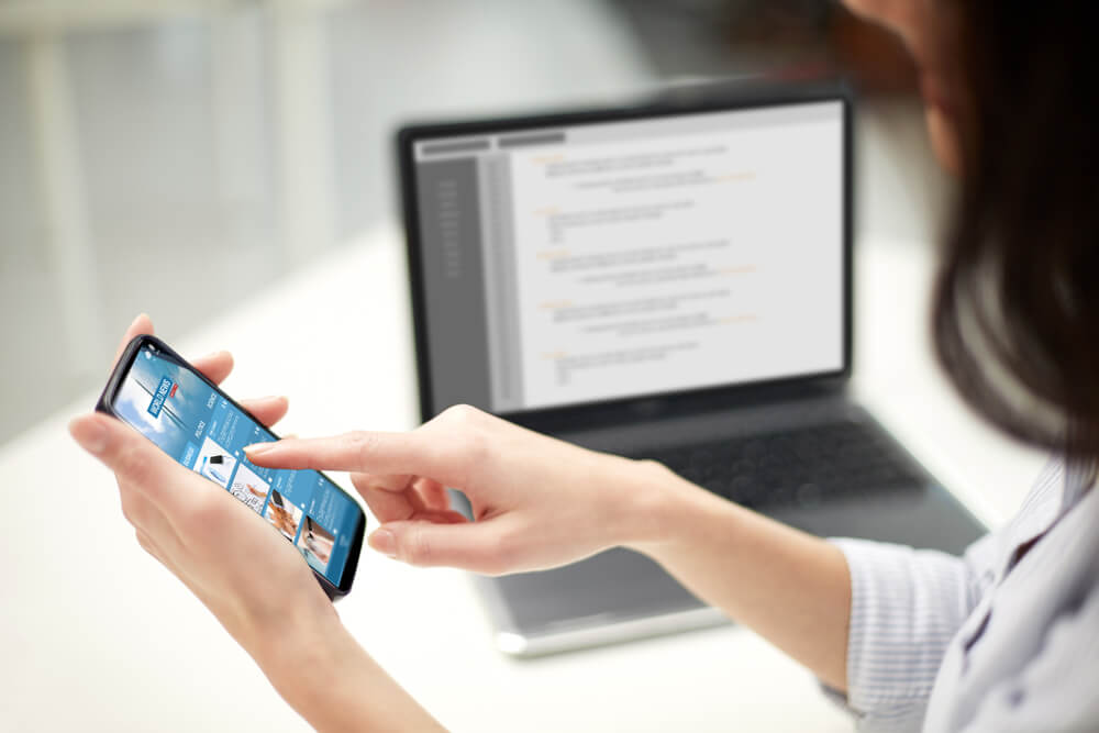 mobile app_business, technology and people concept - close up of woman hands with news web page on smartphone screen at office