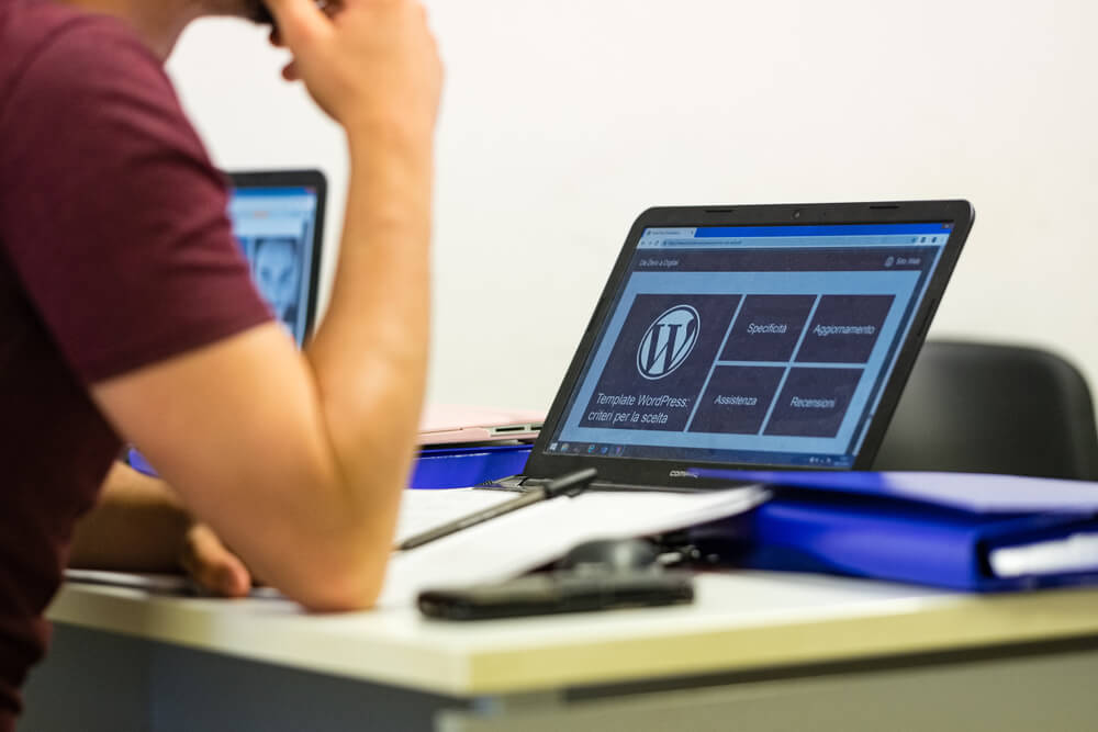 WordPress upload_Taranto, Italy - July 19, 2019: Young student follows the lesson with a laptop in front of him with the Wordpress logo on the display.