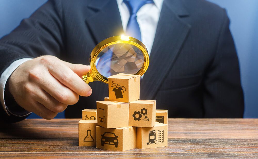 B2B demand_A businessman examines boxes goods with magnifying glass. Market structure research, find unoccupied target consumer niches, demand assessment. Marketing sales promotion strategy. Retailer
