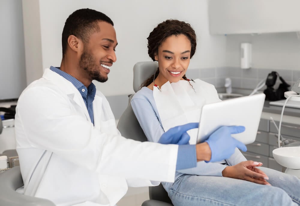 dentist_Happy african american dentist and female patient looking at digital tablet screen, clinic interior