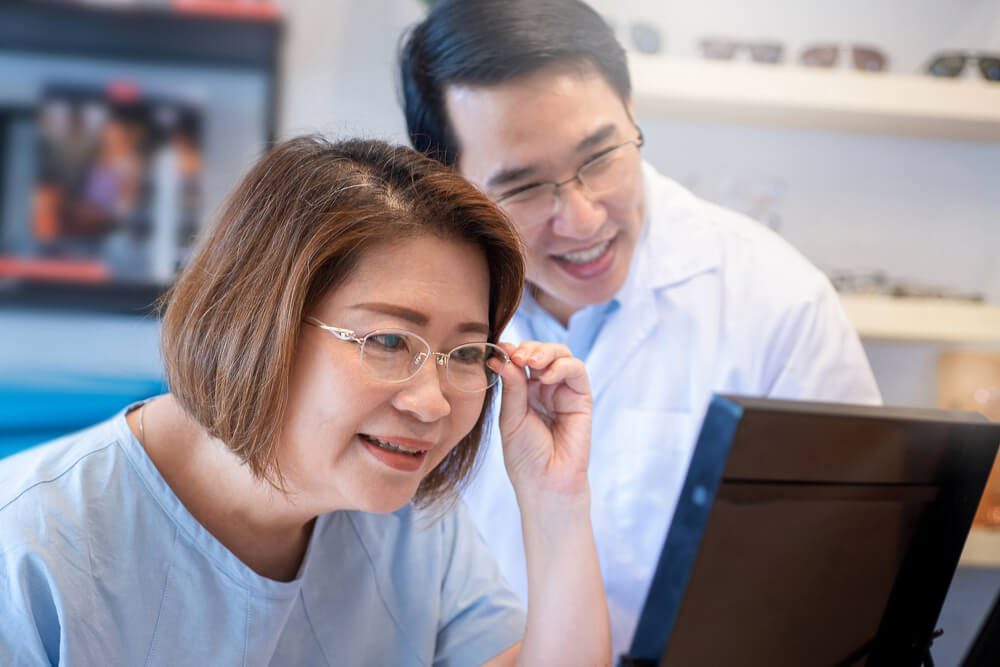 optometry_Asian woman testing new glasses after being advocated by optometry, looking at mirror, selective focus