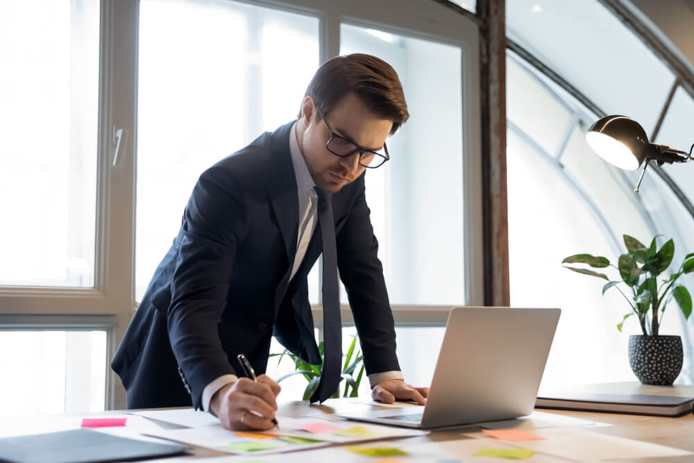 lead and demand_Confident busy young man in formal suit boss executive head of corporate branch checking controlling department work result studying statistic information from financial report and electronic database